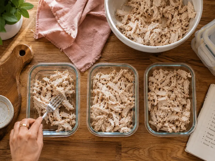 Shredded chicken divided into glass meal prep containers for easy Sunday meal prep — cook once eat twice system